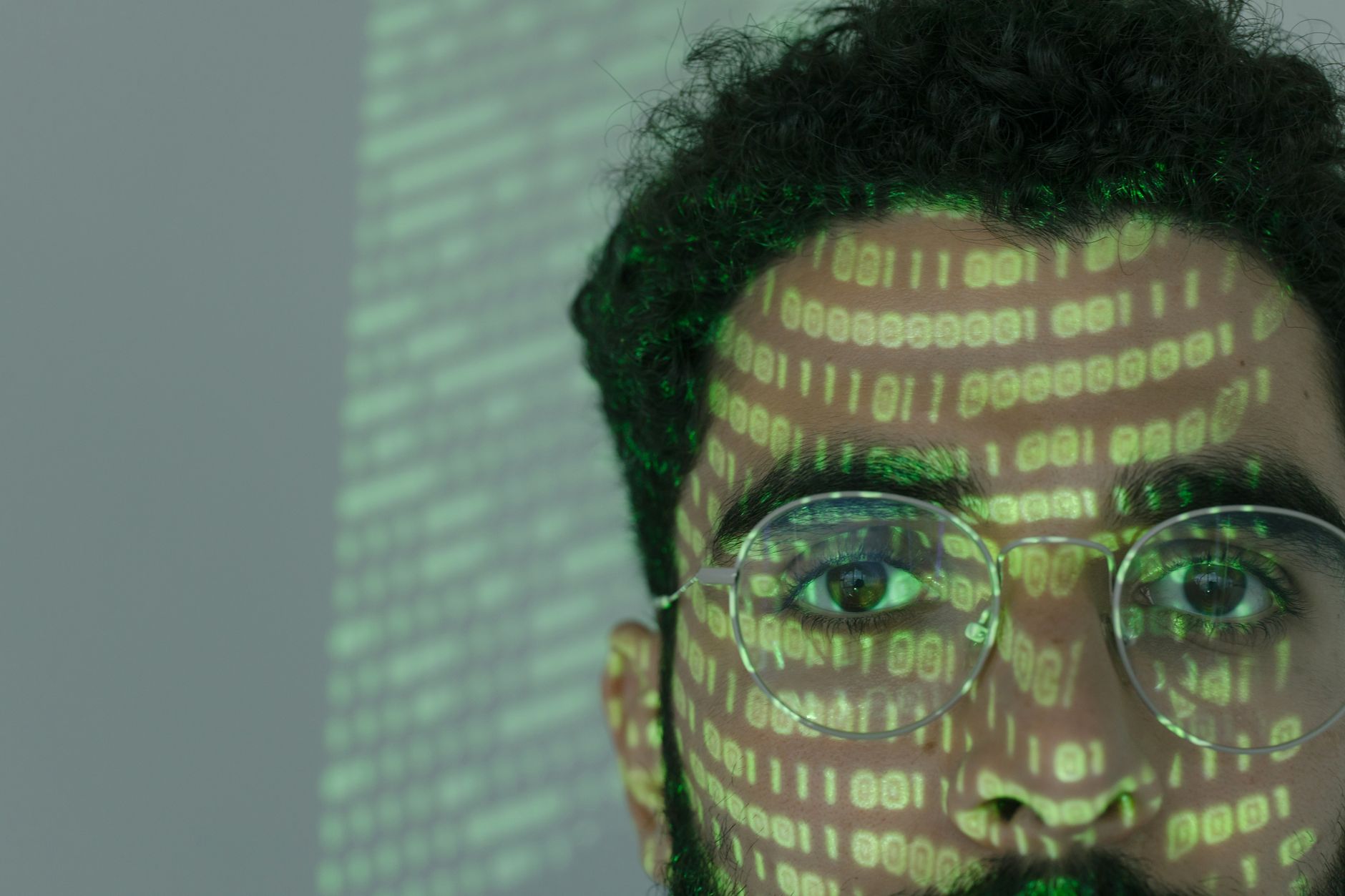 Rosto de um homem sobreposto por códigos binários, em referência à tecnologia digital e à cibersegurança
