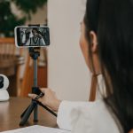 Mulher participa de uma videochamada pelo celular em ambiente interno.