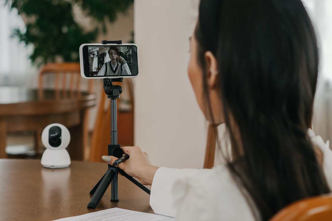 Mulher participa de uma videochamada pelo celular em ambiente interno.